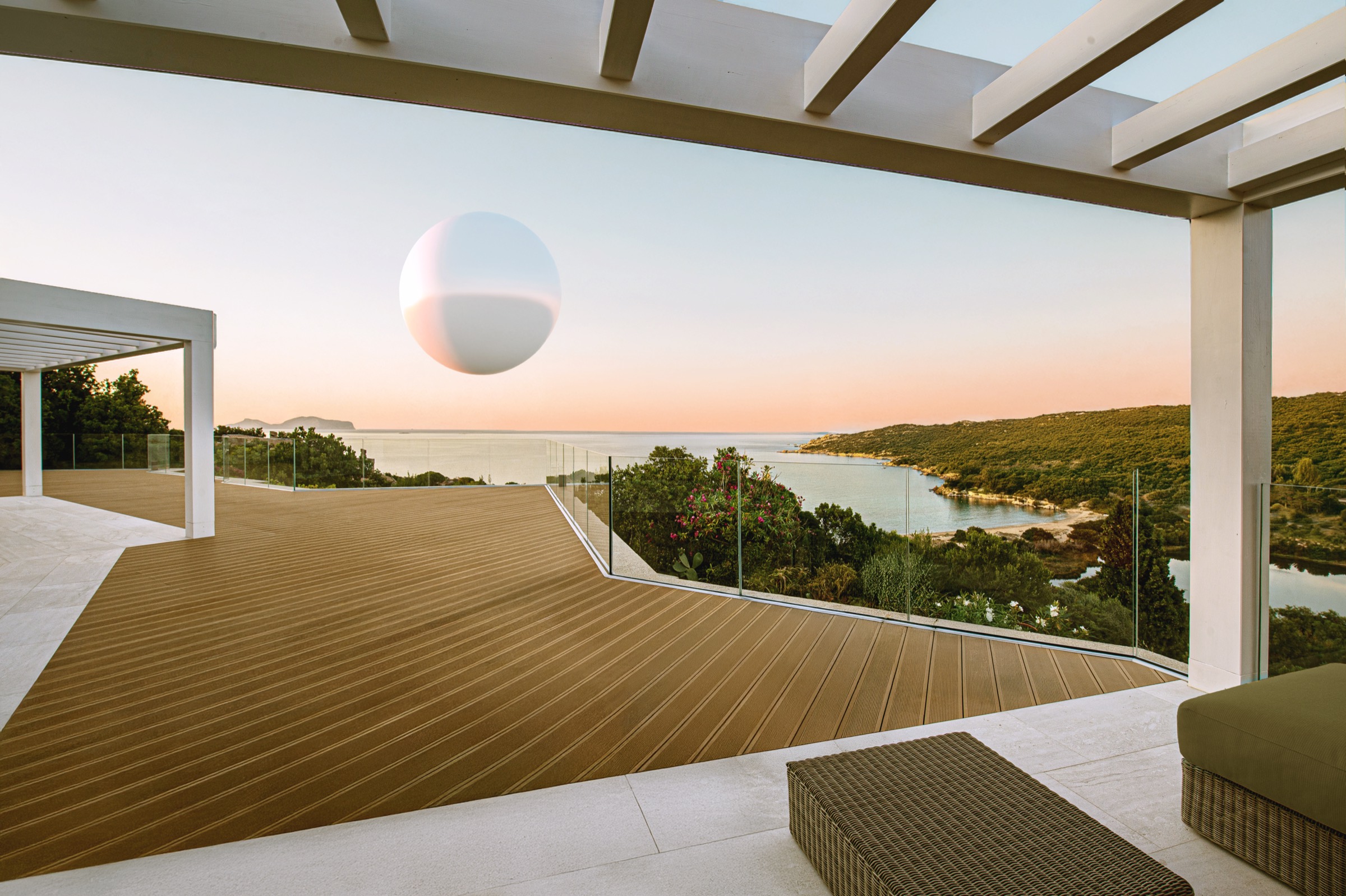 Una grande sfera bianca sospesa sopra una terrazza affacciata sul mare al tramonto